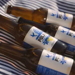 Butelki piwa bezalkoholowego leżą na kocu w paski. Czy piwo bezalkoholowe nawadnia? To pytanie zadaje sobie wielu, a te butelki mogą być odpowiedzią.