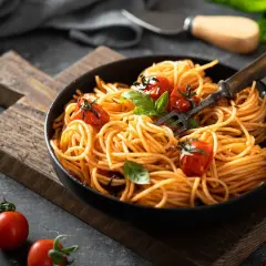 Pyszne danie z makaronem spaghetti w sosie pomidorowym, udekorowane świeżymi pomidorkami i bazylią. Idealne na szybki obiad.