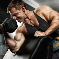 Kulturysta z determinacją ćwiczy biceps, napinając mięsień trójgłowy ramienia podczas podnoszenia ciężaru.