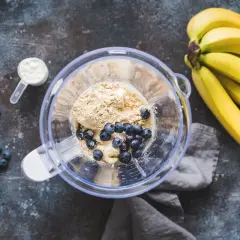 Składniki na pyszny shake proteinowy: banany, borówki, odżywka białkowa w proszku i miętka.
