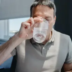 Mężczyzna pije wodę, zastanawiając się, ile pić wody, żeby schudnąć. Woda jest kluczem do zdrowia i metabolizmu.