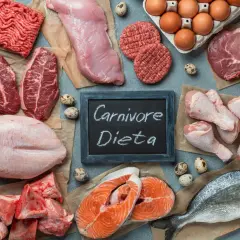 Różnorodne mięsa i ryby, jajka, kości. Tabliczka z napisem "Carnivore Dieta" sugeruje menu dla miłośników mięsa.