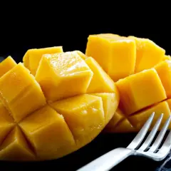 Soczyste, pokrojone w kostkę mango, jak na zdjęciu, budzi pozytywne african mango opinie. Widoczny widelec sugeruje gotowość do degustacji.