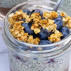 Szybki deser z chia i bananem: pudding chia z jagodami i granolą w słoiku.