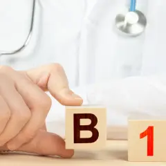 Dłoń lekarza układa kostki z literą B i cyfrą 1. Witamina B1 na co wpływa?