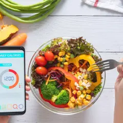 Zdrowa sałatka i smartfon z aplikacją "Daily Calories" pokazującą 1200 kcal. To najlepsza aplikacja do liczenia kalorii, która pomoże Ci osiągnąć cel.