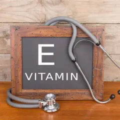 Tablica z napisem "VITAMIN E" i stetoskopem. Witamina E, czyli tokoferol, jest ważna dla zdrowia.