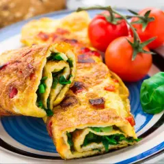 Roladki z omletu z zielonymi warzywami i pomidorkami koktajlowymi. Pyszne śniadanie bez chleba.