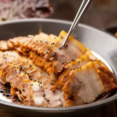 Plasterki gotowanego boczku, posypane czarnym sezamem, idealne na dietę mięsną. Obok widać kimchi.