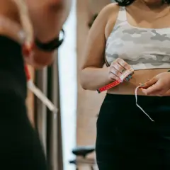 Kobieta mierzy talię centymetrem, widząc efekty chodzenia 5 km dziennie.