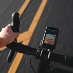 Dłoń na kierownicy roweru, na ekranie nawigacja z trasą i danymi. Ta aplikacja na rower ułatwia jazdę.