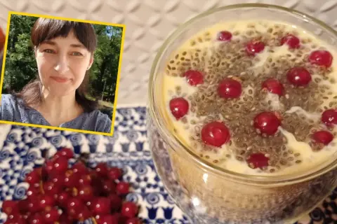 Kobieta uśmiecha się obok deseru z nasionami chia i owocami. Na talerzyku obok leżą czerwone porzeczki.