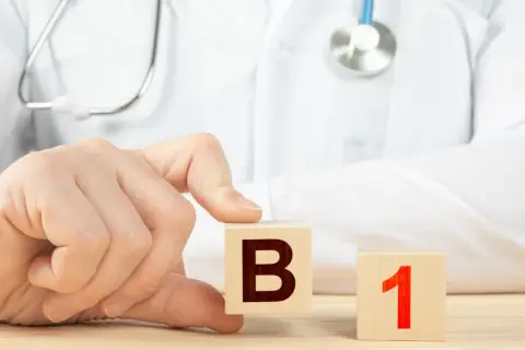 Dłoń lekarza układa kostki z literą B i cyfrą 1. Witamina B1 na co wpływa?