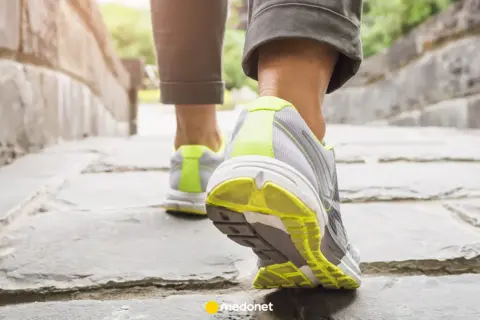 Zbliżenie na nogi w butach sportowych idące po kamiennej ścieżce.