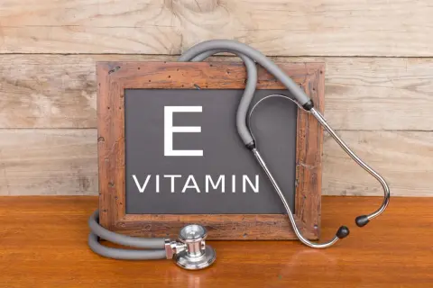 Tablica z napisem "VITAMIN E" i stetoskopem. Witamina E, czyli tokoferol, jest ważna dla zdrowia.