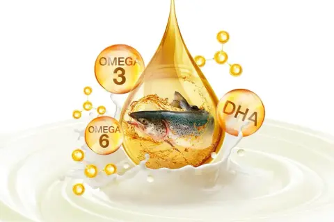 Ryba w kropli oleju, otoczona bańkami z napisami Omega 3, Omega 6 i DHA, symbolizująca zdrowe tłuszcze.
