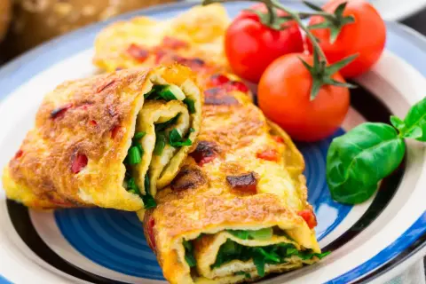 Roladki z omletu z zielonymi warzywami i pomidorkami koktajlowymi. Pyszne śniadanie bez chleba.