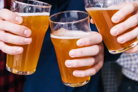 Trzy osoby wznoszą toasty piwem bezalkoholowym. Czy piwo bezalkoholowe jest zdrowe? To pytanie zadaje sobie wielu.