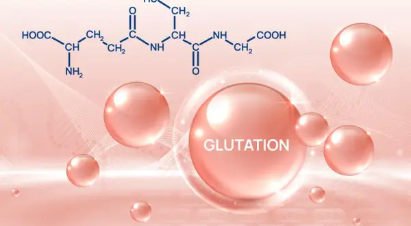 Glutation na co pomaga? Wizerunek przedstawia wzór chemiczny glutationu i różowe kuleczki, symbolizujące jego dobroczynne działanie.