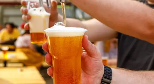 Nalewanie piwa bezalkoholowego do kubka. Zastanawiasz się, ile kalorii ma piwo bezalkoholowe? To świetny wybór na orzeźwienie!