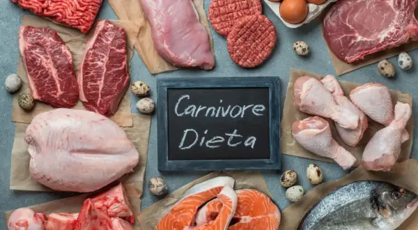 Różnorodne mięsa i ryby, jajka, kości. Tabliczka z napisem "Carnivore Dieta" sugeruje menu dla miłośników mięsa.