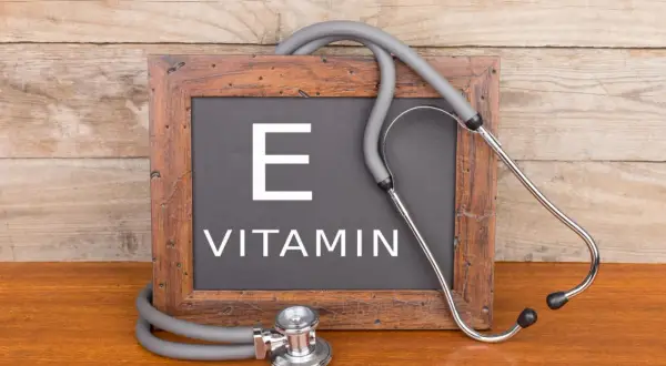 Tablica z napisem "VITAMIN E" i stetoskopem. Witamina E, czyli tokoferol, jest ważna dla zdrowia.