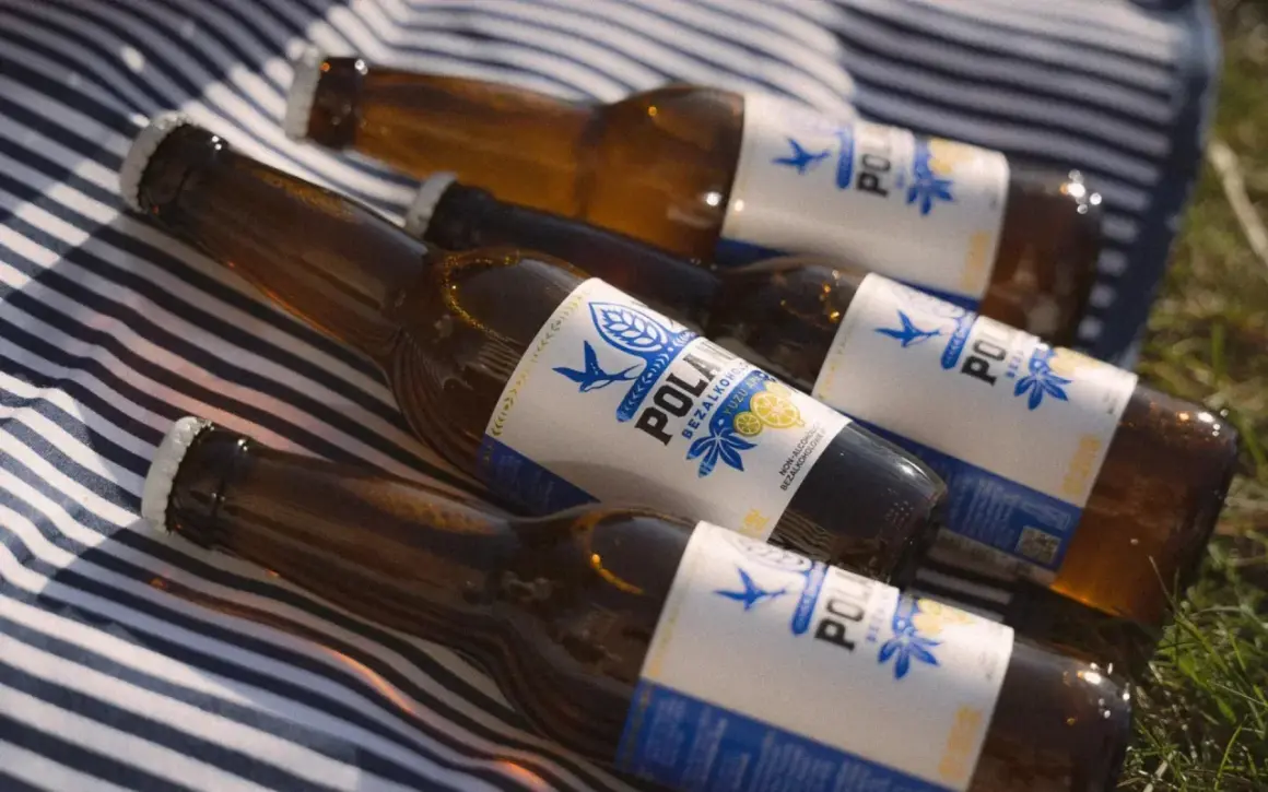 Butelki piwa bezalkoholowego leżą na kocu w paski. Czy piwo bezalkoholowe nawadnia? To pytanie zadaje sobie wielu, a te butelki mogą być odpowiedzią.