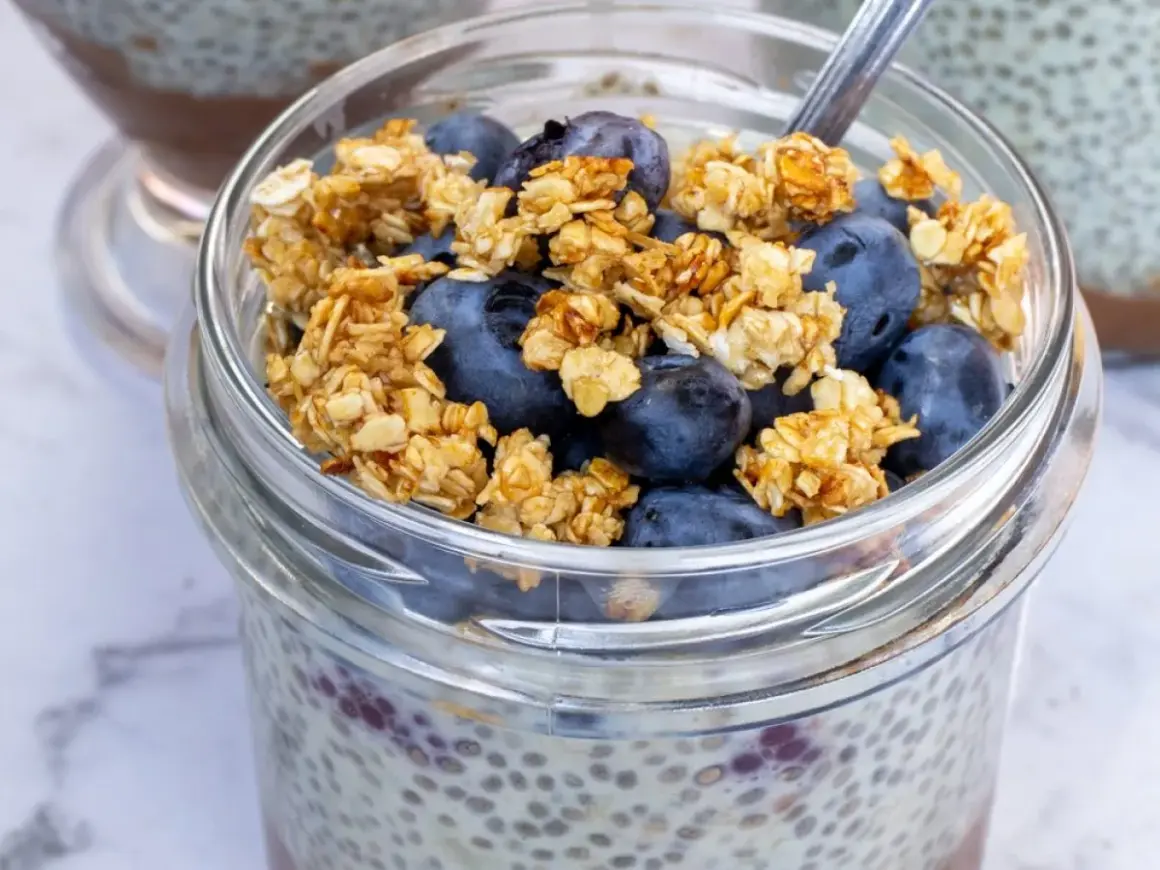 Szybki deser z chia i bananem: pudding chia z jagodami i granolą w słoiku.