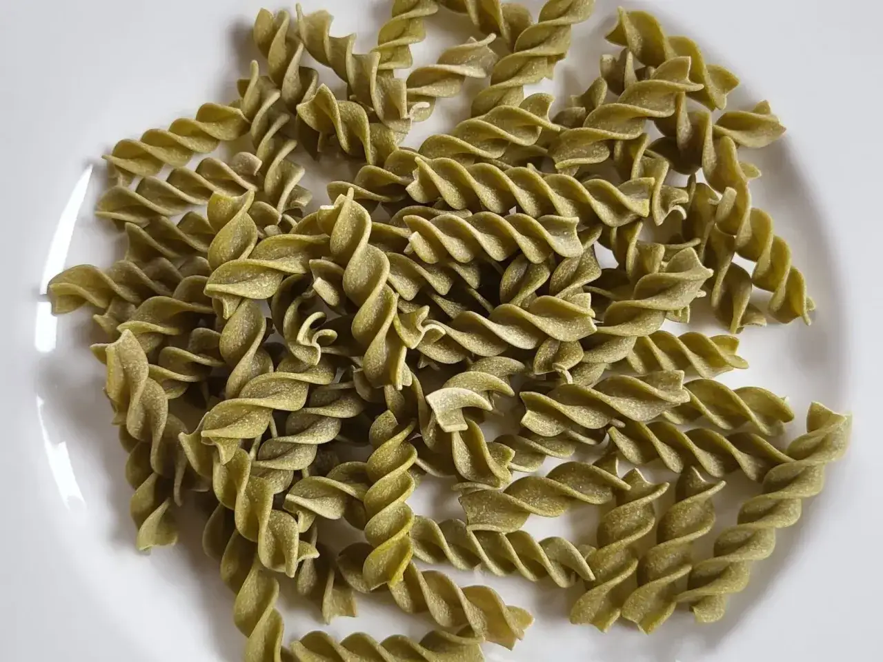 Zielone fusilli, czyli makaron z zielonego groszku, ułożone na białym talerzu. Idealne do lekkich, wiosennych dań.