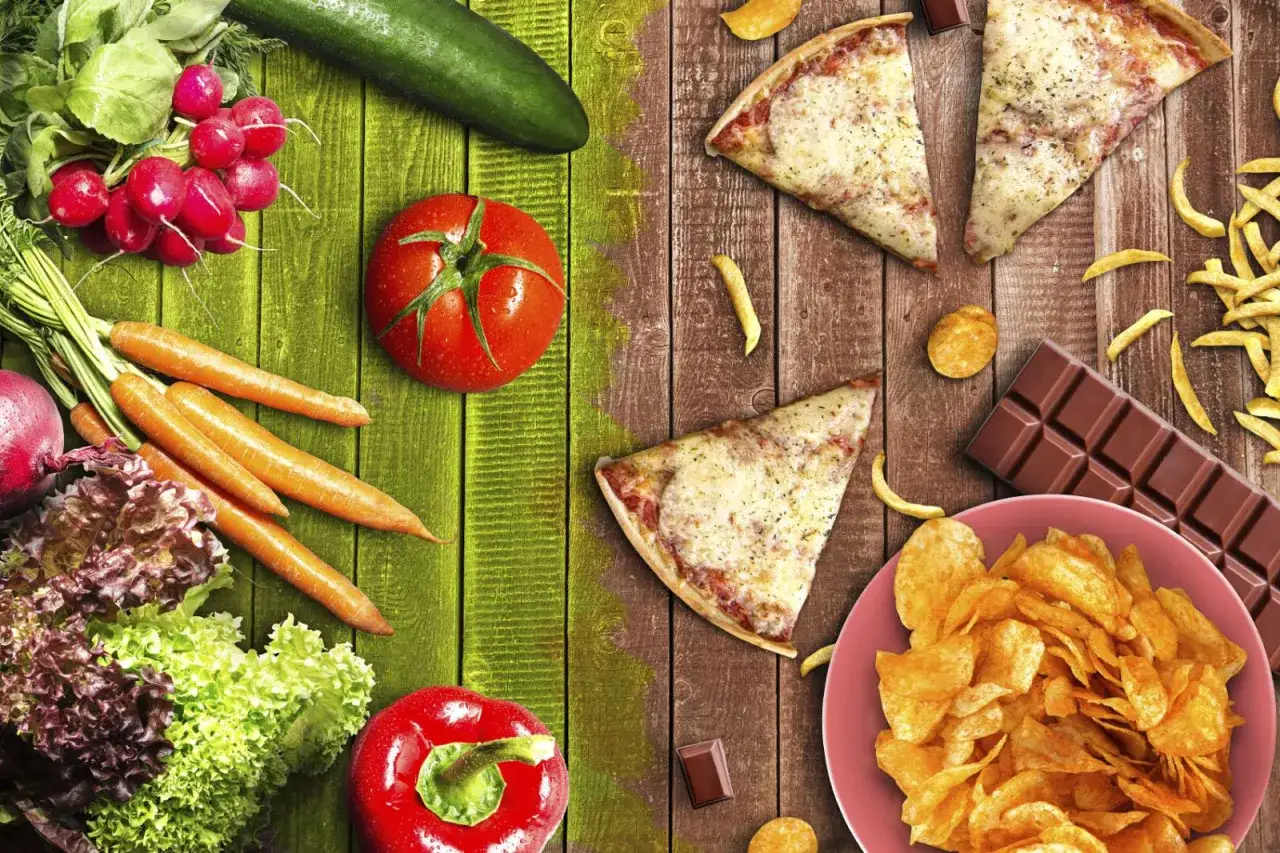 Zdrowe warzywa po lewej, po prawej kuszące niezdrowe jedzenie: pizza, frytki, chipsy, czekolada.