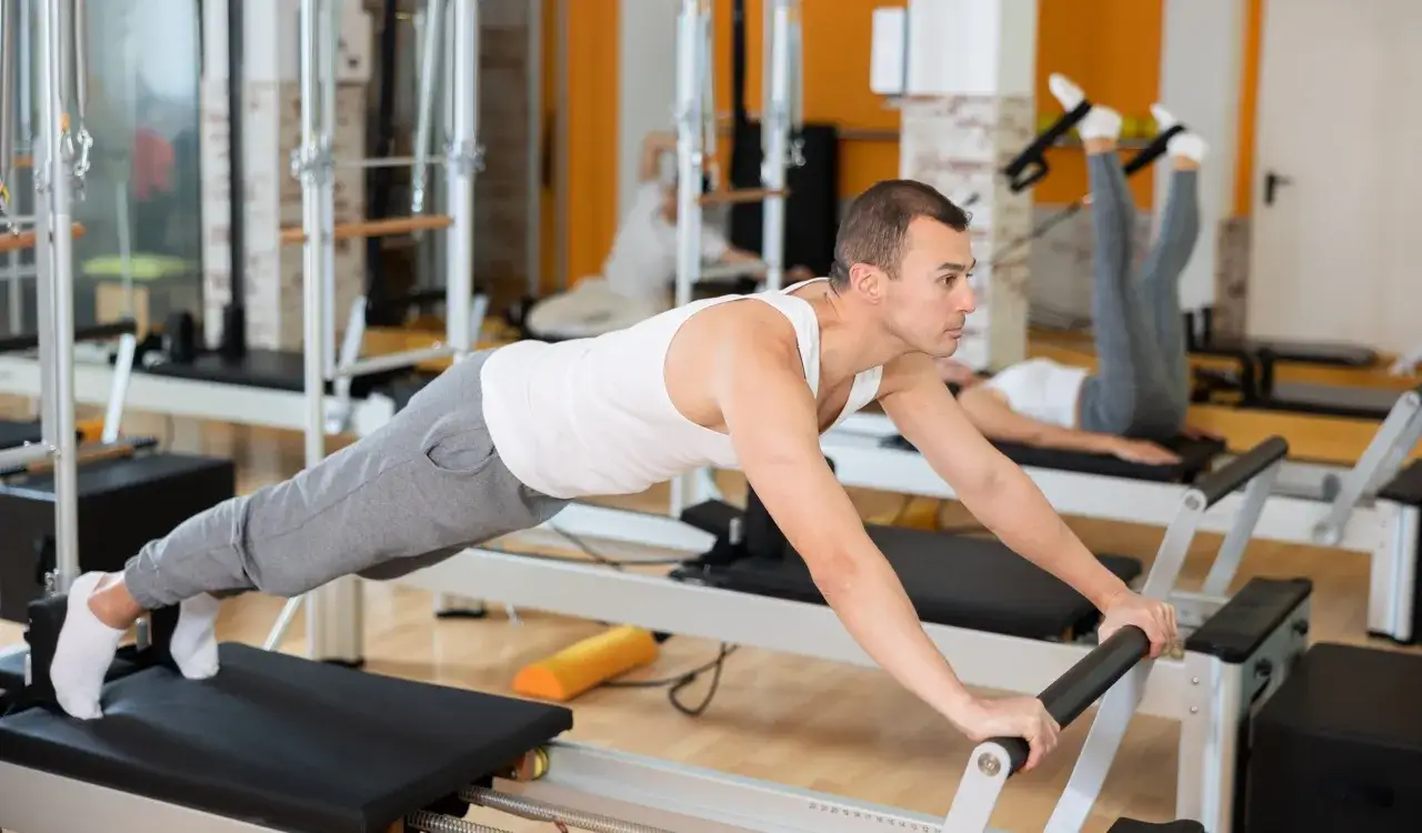 Mężczyzna i kobieta ćwiczą na reformerach pilates. Czy pilates odchudza? Tak, regularne ćwiczenia wzmacniają ciało i mogą pomóc w redukcji wagi.