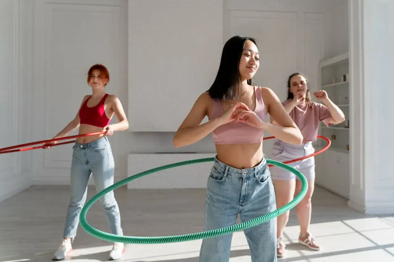 Trzy dziewczyny kręcą hula hop. Widać pierwsze efekty po 2 tygodniach ćwiczeń.