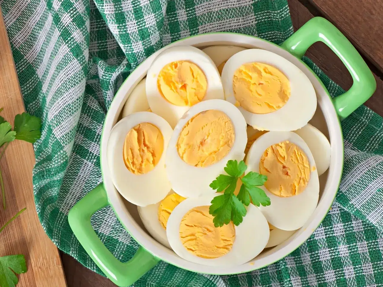 Połówki jajek na twardo w zielonej misce, ozdobione natką pietruszki. Czy jajka a cholesterol to mit?
