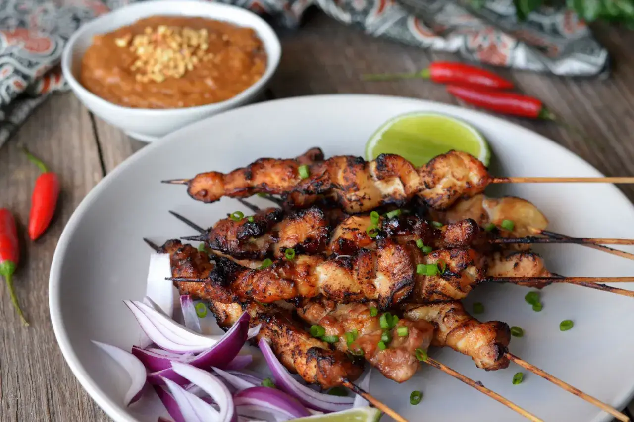 Aksamitne satay z kurczaka, grillowane do perfekcji, podane z orzechowym sosem, czerwoną cebulą i limonką.