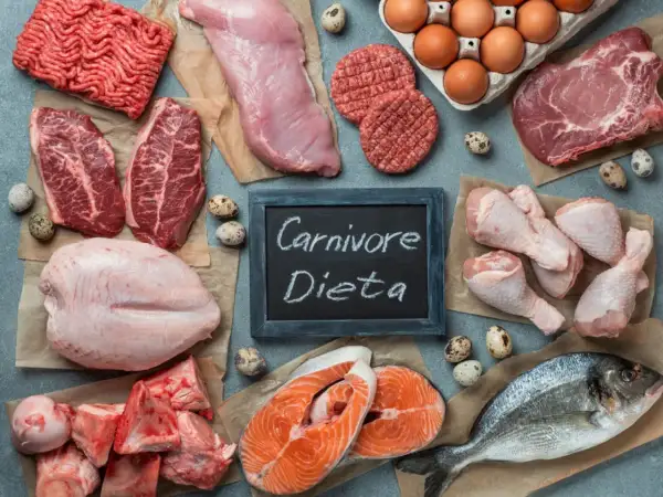 Różnorodne mięsa i ryby, jajka, kości. Tabliczka z napisem "Carnivore Dieta" sugeruje menu dla miłośników mięsa.