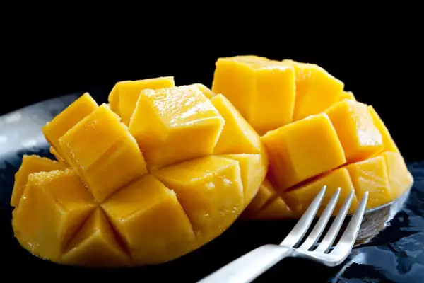 Soczyste, pokrojone w kostkę mango, jak na zdjęciu, budzi pozytywne african mango opinie. Widoczny widelec sugeruje gotowość do degustacji.