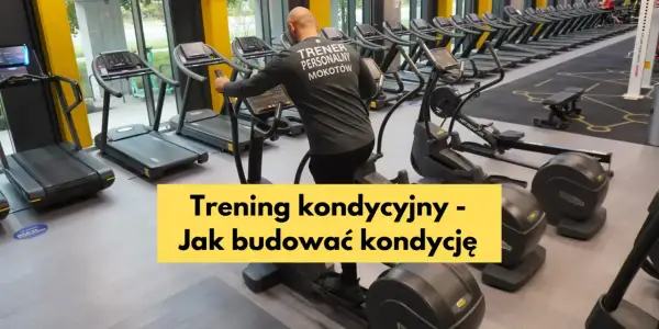 Mężczyzna w koszulce "Trener Personalny Mokotów" ćwiczy na orbitreku. W tle bieżnie i inne maszyny cardio, idealne do treningu kondycyjnego.