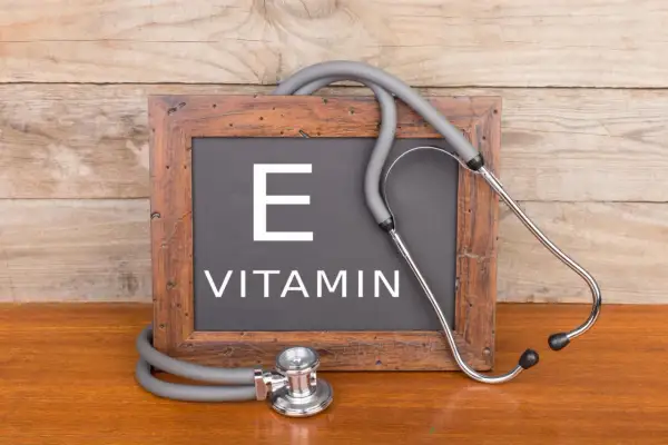 Tablica z napisem "VITAMIN E" i stetoskopem. Witamina E, czyli tokoferol, jest ważna dla zdrowia.
